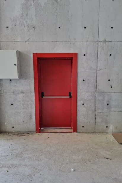Beton duvarda panik barlı kırmızı çelik yangın kapısı